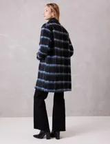 Tapado símil mohair, marca Dictionary, con estampado a cuadros en negro y azul. Tiene cuello con solapa, cierre frontal con botones y bolsillos delanteros. Incluye forro interno a tono.