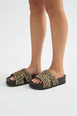 Sandalia plana con plataforma negra y tira ancha de pelo con estampado animal print tipo leopardo, decorada con tachas metálicas en los bordes.
