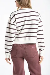 Sweater de algodón con diseño de rayas horizontales en color marrón sobre fondo crudo. Presenta un corte oversize, cuello redondo y puños acanalados, con un pequeño detalle bordado en la parte inferior.