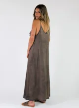 Vestido largo sin mangas de color marrón con efecto gastado, tirantes finos, escote en V con volados y gran volante central delantero que recorre toda la prenda. Cuenta con bolsillos laterales.