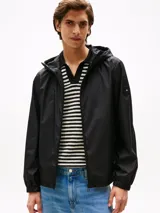 Campera rompeviento de poliéster reciclado con capucha ajustable. Presenta un diseño liso en color negro, cierre frontal completo, puños elásticos y el logo de Tommy Hilfiger engomado en la manga.