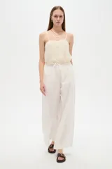 Pantalón de lino color blanco, de corte ancho y tiro alto, con cintura elastizada y cordón ajustable.