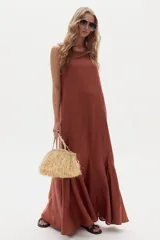 Vestido largo de lino marrón, sin mangas, con cuello a la base y canesú en la espalda. Cuenta con godets en el ruedo que le aportan movimiento y amplitud.