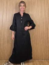 Vestido largo tipo túnica de color negro, con cuello mao, escote en V con botones frontales, y mangas tres cuartos con volados dobles.