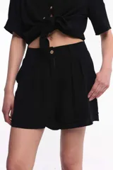Short negro de algodón con pinzas, tiro alto, pretina con botón frontal y bolsillos laterales.