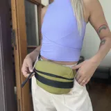 Riñonera gris confeccionada en nylon liviano con cinta de poliéster tejida horizontal en el frente y logo "Lincoln's" bordado. Cuenta con bolsillo interno con cierre y correa de galón regulable.