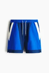 Short de baño y deportivo confeccionado en nylon, de corte holgado. Presenta un diseño de bloques de color en tonos azul, azul marino y blanco. Cuenta con cintura elástica con cordón ajustable blanco, bolsillos laterales y aberturas en los costados del ruedo. Incluye suspensor interno de malla.