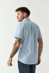 Camisa de manga corta con estampado de cuadros vichy en azul y blanco. Presenta cuello con botones, cierre frontal con botones y logo bordado en el pecho.