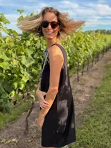 Vestido corto negro de gabardina con corte suelto y escote en V en frente y espalda. La parte delantera está adornada con flecos de lentejuelas plateadas.