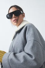 Campera corta de paño color gris con cuello de corderito blanco, cierre frontal con botones y bolsillos laterales.