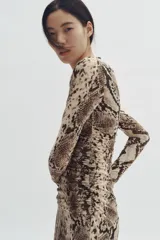 Vestido largo de malla de doble capa con estampado de piel de serpiente. Modelo entallado de manga larga, con escote redondo y detalle de costura fruncida lateral que crea un efecto drapeado.