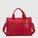 Tote bag color rojo de diseño funcional, con doble asa de mano y correa ajustable extraíble. Presenta bandas verticales con el logo de la marca estampado y un dije colgante con la letra B en color rosado.