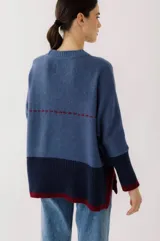 Buzo de lana color beige con bloques de color ocre y bordó en mangas y ruedo. Presenta un bolsillo pequeño en el pecho y costuras decorativas en color bordó.