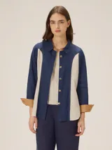 Camisa de lino de manga larga con diseño bicolor en azul marino y beige, con cuello clásico, botones frontales y puños vueltos en tono tostado.