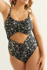 Malla entera estampada en blanco y negro con escote cruzado, cut out en el abdomen y detalle de frunce. Presenta una flor removible en el escote y breteles finos regulables al cuello.