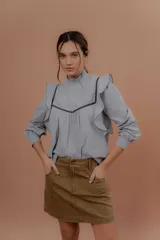 Minifalda de gabardina color tostado, de tiro medio con bolsillos delanteros y traseros, presillas para cinto y cierre frontal con botón metálico.