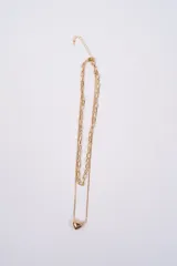 Collar doble de cadena dorada, compuesto por una cadena de eslabones rectangulares y una cadena fina tipo serpiente con un dije de corazón liso.