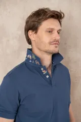 Chomba azul de piqué de algodón con cuello polo, tapeta de dos botones con diseño estampado en el interior y mangas cortas. Corte clásico.
