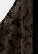 Vestido largo marrón con diseño asimétrico de un solo hombro, confeccionado en tela de terciopelo con estampado flocado de motivos florales y botánicos.