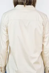 Camisa de corte clásico color camel, confeccionada en algodón, con cuello camisero, cierre frontal de botones y mangas largas con puños abotonados.