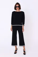 Conjunto de dos piezas de tejido de punto en color blanco con detalles de bordes en negro. Incluye un sweater de corte recto con mangas tres cuartos y un pantalón de corte amplio y largo cropped.