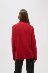 Polera de tejido de punto color crema, con cuello alto y diseño de trenzas verticales. Presenta mangas largas con puños acanalados y un corte holgado.