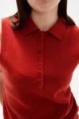 Chaleco de punto color rojo, con cuello polo y cierre frontal de botones. Diseño sin mangas y corte al cuerpo.