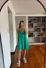 Vestido corto color verde esmeralda, de silueta holgada y tirantes finos. Presenta un escote en V con detalle de cordones cruzados en el frente.