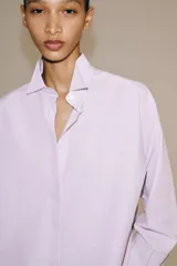 Camisa de manga larga confeccionada en hilatura con mezcla de algodón, con cuello solapa, bajo redondeado y cierre frontal oculto con botones.