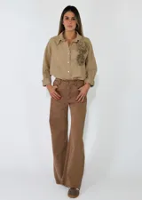 Pantalon de corte recto y tiro medio, confeccionado en gabardina color marrón. Presenta cierre frontal con botón y bolsillos laterales.