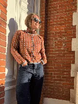 Cardigan reversible de punto con estampado de rombos pequeños, cuello alto y cierre frontal completo con botones. Presenta detalles de ribetes en color contrastante en cuello, puños y cartera de botones.