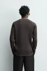 Remera de manga larga de corte regular fit, confeccionada en tejido acanalado con mezcla de algodón y efecto lavado. Cuenta con cuello redondo y cierre frontal corto con tres botones.