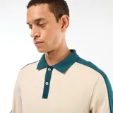 Remera polo de manga larga con diseño bicolor, combinando cuerpo en color beige con cuello, tapeta de botones y mangas en color verde oscuro.