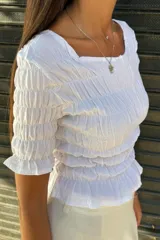 Remera negra de algodón con textura fruncida en todo el cuerpo y mangas cortas con terminación de volado.