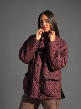 Campera marrón oscuro capitoneada, con diseño acolchado de rombos, cuello alto, cierre frontal con botones metálicos y grandes bolsillos aplicados con solapa en el frente.