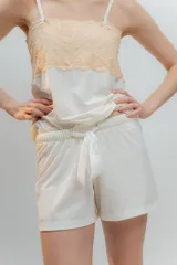 Pijama de dos piezas, compuesto por una musculosa blanca con detalle de puntilla negra elástica en el escote y un short blanco con elástico y lazo negro en la cintura.