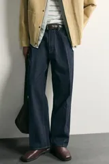 Pantalón jean azul marino oscuro de corte recto y holgado, largo cropped, tiro medio y tejido rígido de denim sin lavado. Cuenta con diseño de cinco bolsillos y costuras en tono tabaco contrastante.