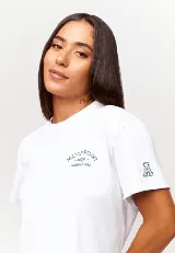 Remera blanca de algodón con corte crop, mangas cortas y estampado frontal con texto y logo en color gris.