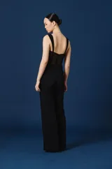 Mono largo negro con diseño tipo corset en el torso, con copas estructuradas y paneles de encaje semitransparente. Presenta breteles anchos y se complementa con una estola de tul negro incorporada.