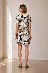 Vestido corto con cuello redondo y mangas cortas, de corte recto y holgado, con estampado abstracto en tonos beige, verde oscuro y violeta.