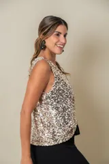 Blusa sin mangas confeccionada en tela cubierta de lentejuelas doradas y plateadas, con escote redondo y corte holgado.