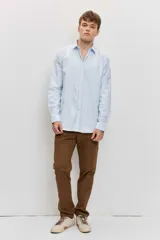 Camisa de manga larga con cierre frontal de botones y cuello clásico, color celeste con sutiles rayas verticales.
