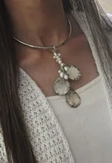 Gargantilla rígida plateada con dije colgante de tres monedas texturadas y detalles de perlas.