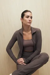 Campera deportiva de textura acanalada, color negro, con cierre frontal, cuello alto y mangas largas con orificio para el pulgar.