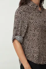 Camisa de manga tres cuartos con estampado de leopardo en tonos beige y negro, cuello camisero y botones frontales.