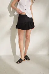 Minifalda negra de talle alto con volado en el ruedo.