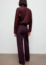 Pantalon de corte recto en color morado oscuro, con tiro medio y detalle de ribete (piping) en contraste a lo largo de las piernas. Cuenta con bolsillos laterales, cierre oculto y trabillas para cinturón.