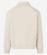 Campera masculina de corte boxy en color beige, con cuello inglés, cierre frontal de cremallera, mangas largas con puños elásticos y ruedo con elástico. Presenta bolsillos laterales y detalles de recortes en el diseño.