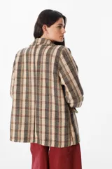 Blazer de corte recto con estampado de cuadros en tonos marrones, beige y rojos. Presenta solapas clásicas, cierre frontal con un botón y bolsillos laterales con solapa.