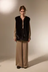 Chaleco sin mangas de piel sintética en color negro, con diseño abierto y corte recto.